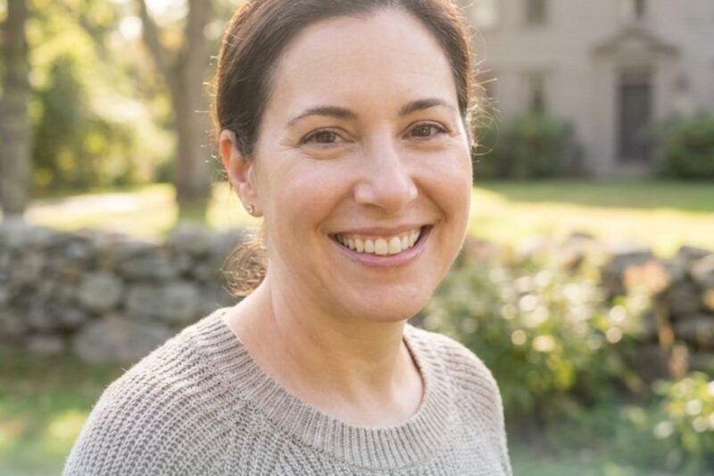 Smiling woman outdoors with natural background, promoting skin care.