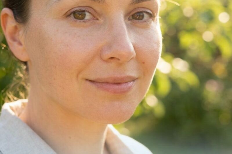 Woman smiling in sunlight, text about hyperpigmentation.
