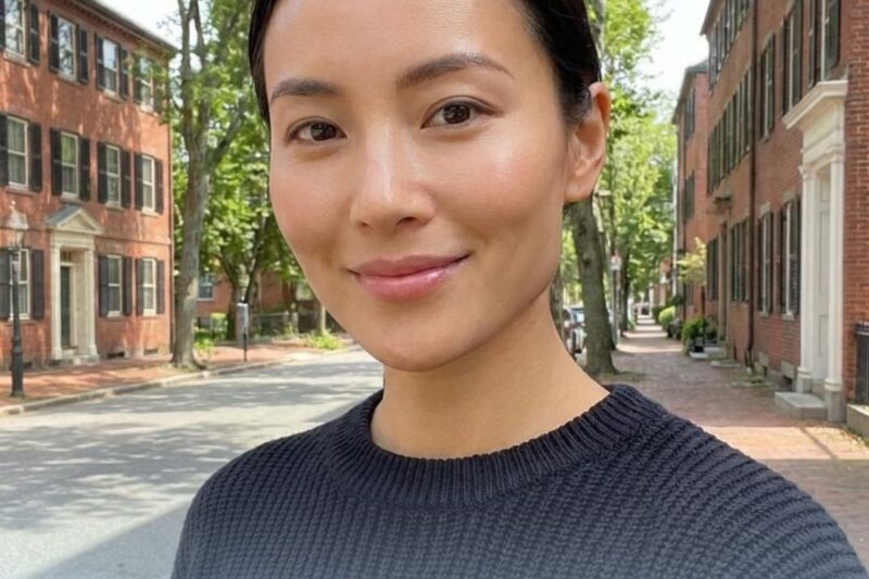 Woman smiling on a tree-lined street.