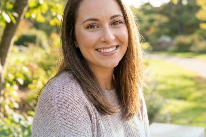 Smiling woman outdoors promoting skin treatment.