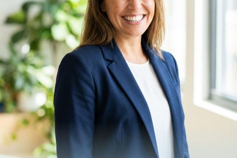 Smiling woman in a blue blazer indoors.