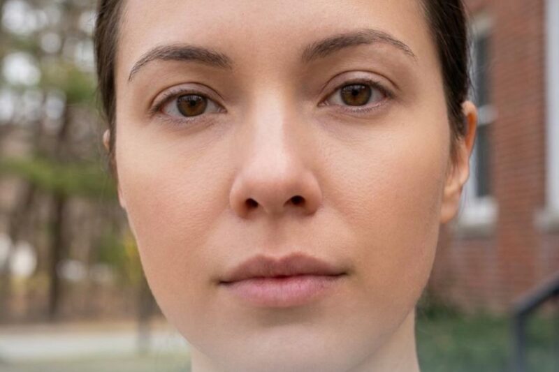 Close-up of a woman touching her cheek with text about tightening enlarged pores.